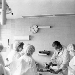 Willy Peers examinant un bébé après un accouchement avec plusieurs infirmières autour de lui