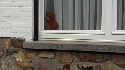 Nounours brun "esseulé", au bord d'une fenêtre