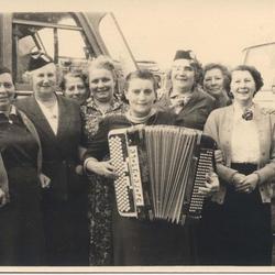 Groupe de femmes avec un accordéon devant des bus